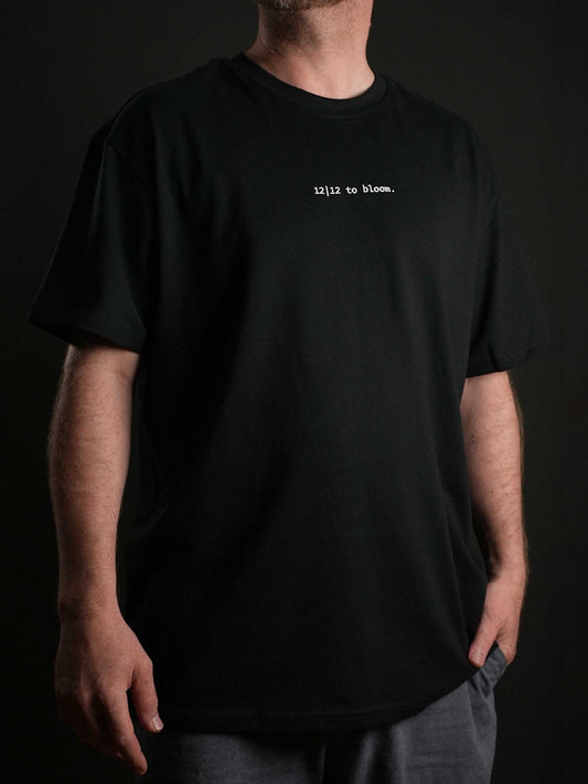 „Das 12|12 to bloom T-Shirt in Schwarz mit dezentem gestickten Schriftzug auf der Vorderseite – minimalistisch & stylisch
