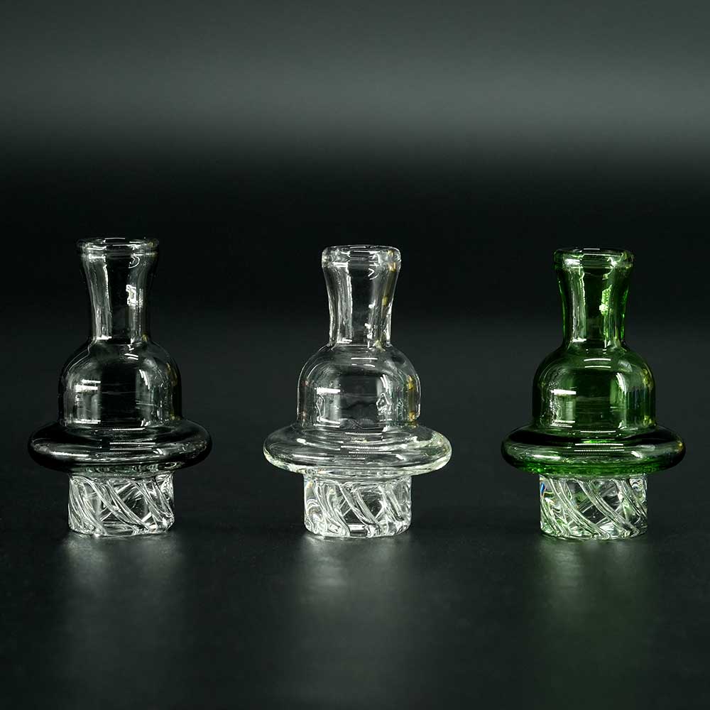 Carb Cap Spinner aus Borosilikatglas – drei Farben klar, schwarz und grün nebeneinander.