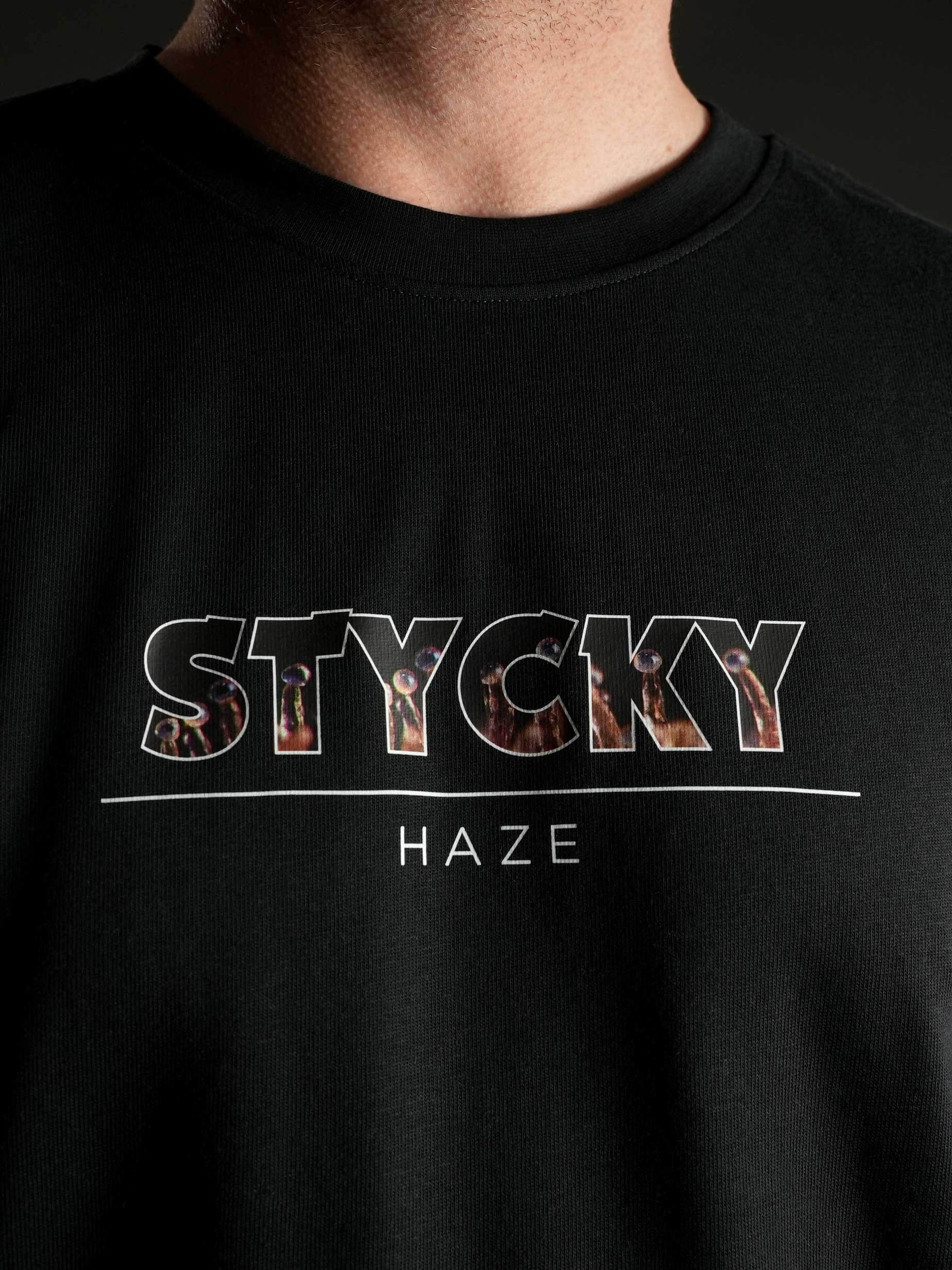 Nahaufnahme des auffälligen ‚STYCKY Haze‘ Motivs auf dem schwarzen T-Shirt